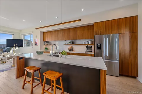 a kitchen with stainless steel appliances a refrigerator a sink a stove a dining table and chairs