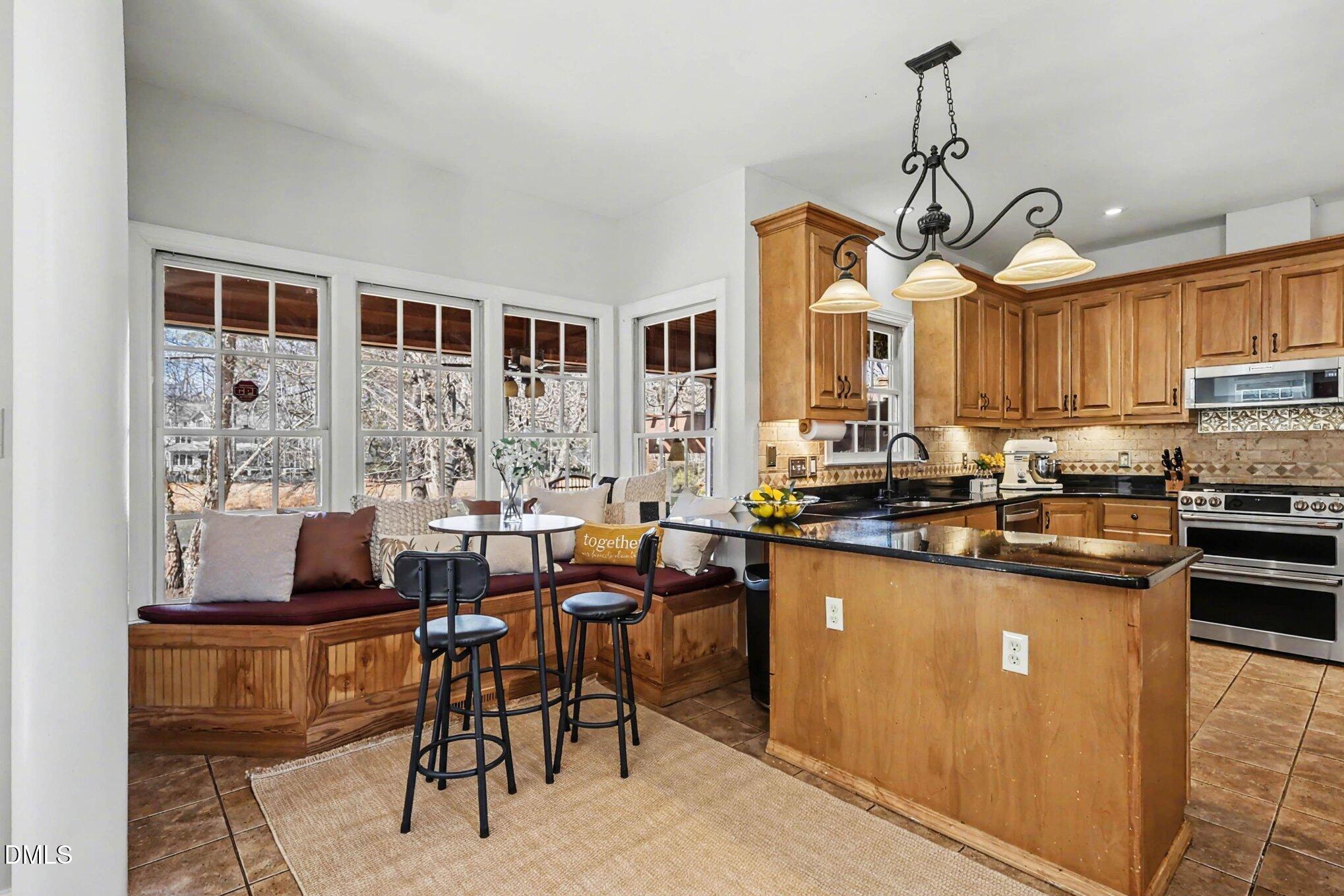 119 Felspar Way Cary, NC 27518 - Photo 12 of 53 a kitchen with stainless steel appliances granite countertop a stove top oven a sink a dining table and chairs with wooden floor