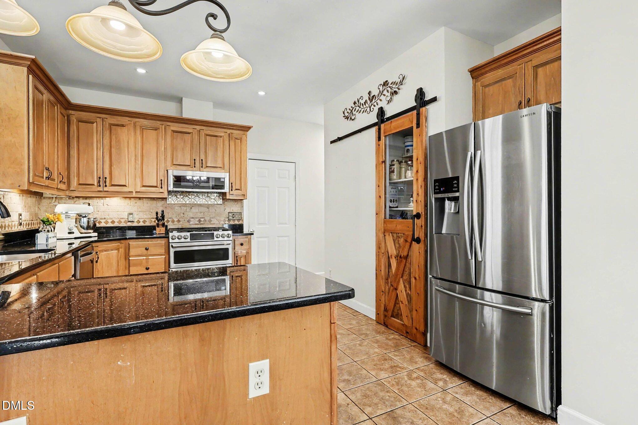 119 Felspar Way Cary, NC 27518 - Photo 15 of 53 a kitchen with stainless steel appliances granite countertop a refrigerator a stove and a sink with granite countertops