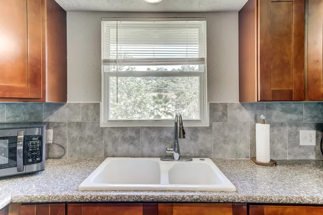 a kitchen with stainless steel appliances granite countertop wooden cabinets a stove top oven a sink and dishwasher with wooden floor