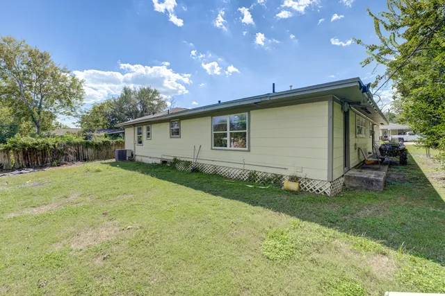 a backyard of a house with table and chairs plants and large tree