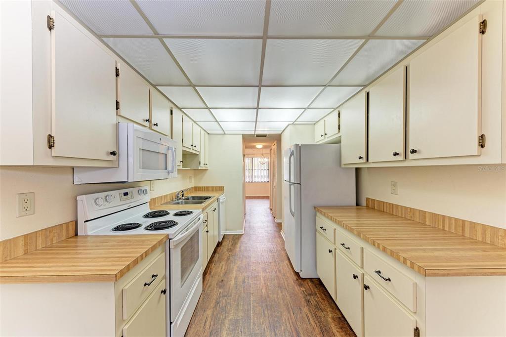 305 30th Avenue West, Unit A210 Bradenton, FL 34205 - Photo 13 of 33 a kitchen with granite countertop a stove a sink a refrigerator and white cabinets with wooden floor