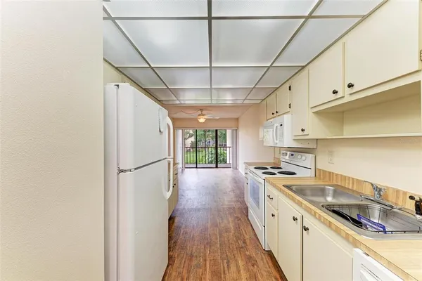 a kitchen with granite countertop a sink a counter space wooden floor and stainless steel appliances