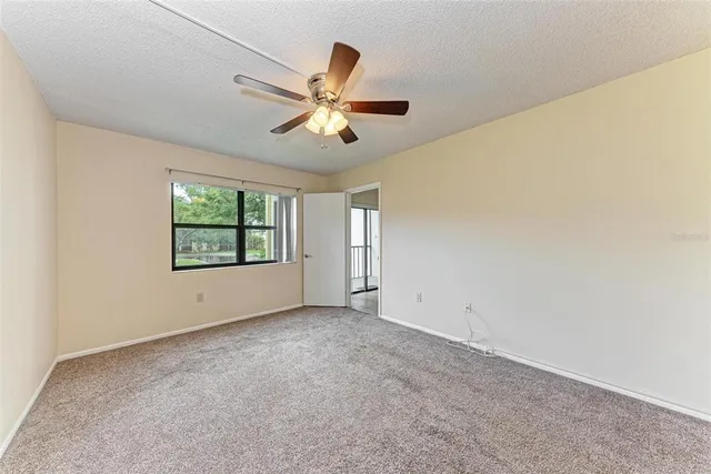 an empty room with windows and ceiling fan