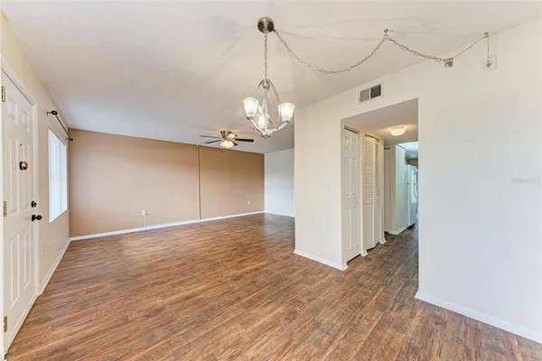 a view of a hallway with wooden floor and a chandelier