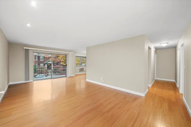 a view of an empty room with wooden floor and a window