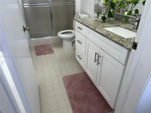 a bathroom with a granite countertop sink a toilet and a mirror