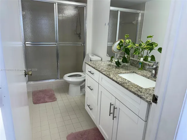 a bathroom with a granite countertop sink a toilet and a mirror
