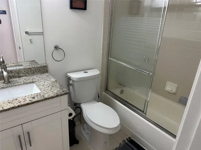 a bathroom with a granite countertop toilet sink and shower