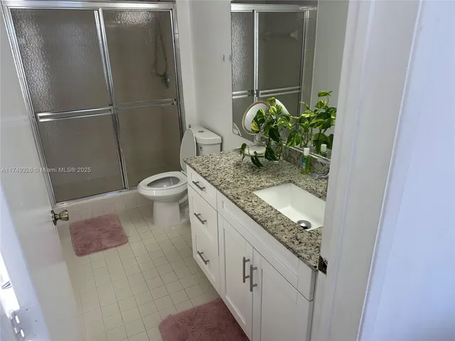 a bathroom with a granite countertop sink a toilet and shower