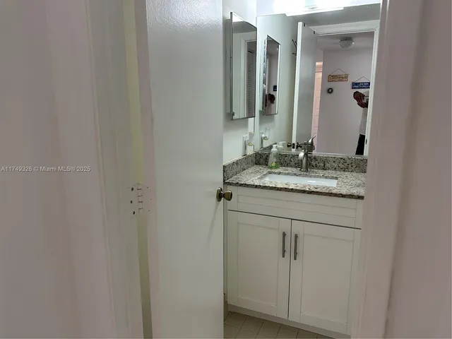 a bathroom with a granite countertop sink and mirror