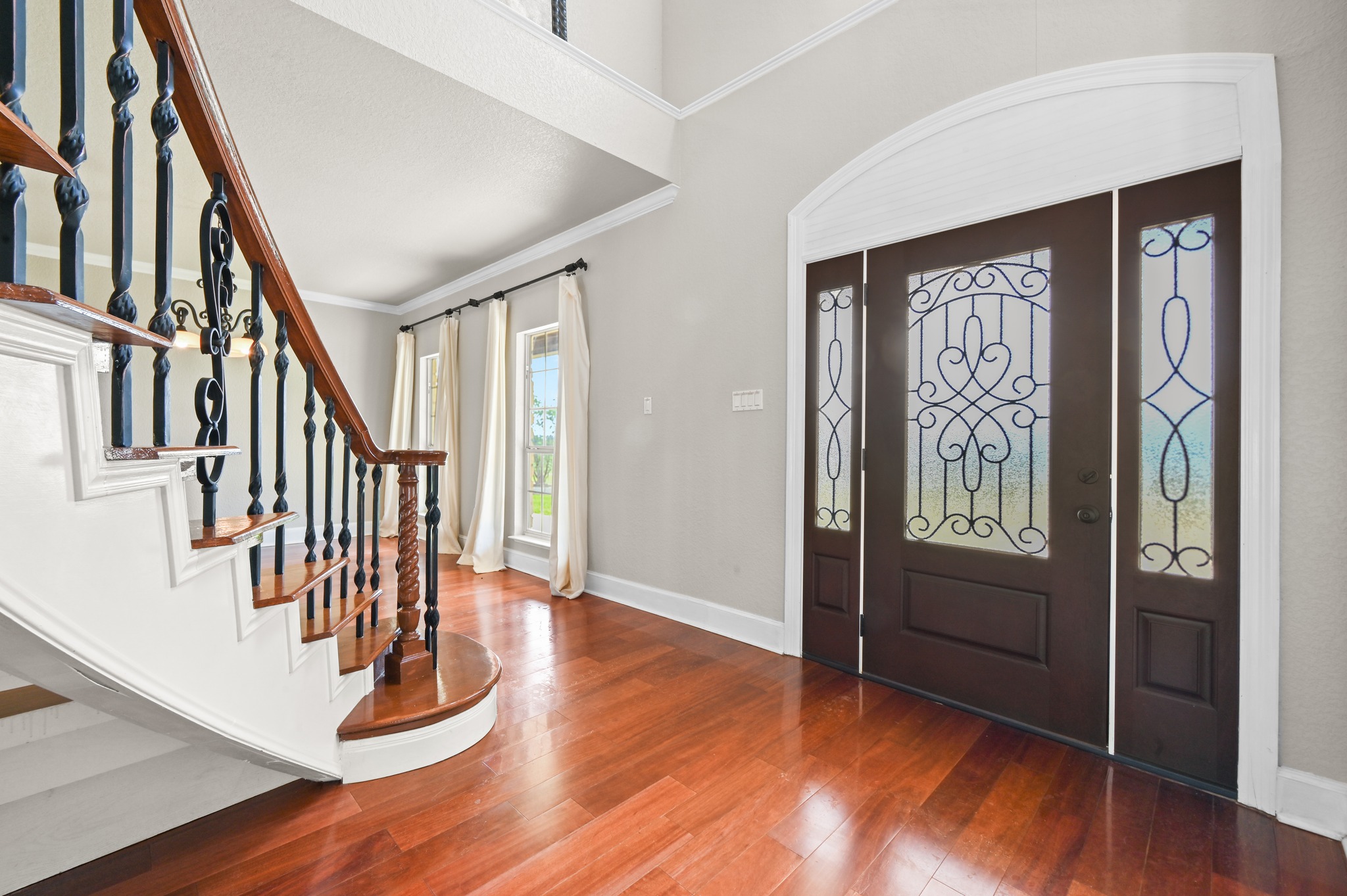 1175 Southern Way Luling, TX 78648 - Photo 15 of 40 A grand entryway features a graceful curved staircase, rich wood flooring, and an ornate leaded-glass door.