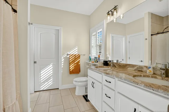 a bathroom with a granite countertop sink mirror and toilet