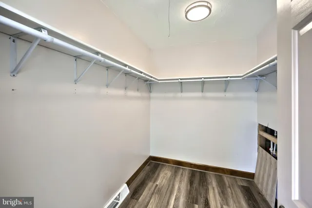 a view of walk in closet with window and hardwood floor
