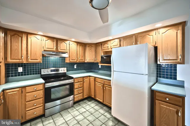 a kitchen with stainless steel appliances granite countertop a stove top oven a sink dishwasher a refrigerator and white cabinets with wooden floor