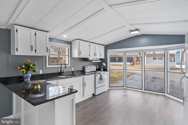 a kitchen with granite countertop a sink stainless steel appliances and white cabinets