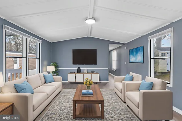 a living room with furniture a flat screen tv and a large window