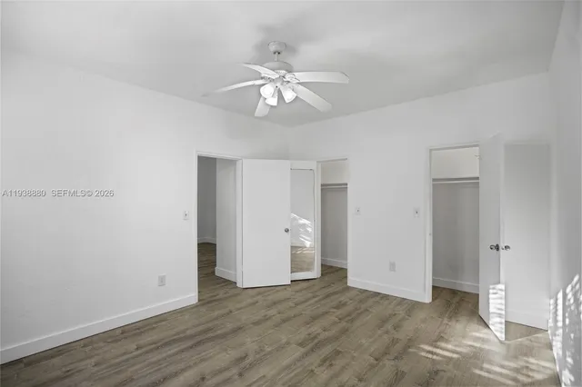 an empty room with wooden floor and ceiling fan