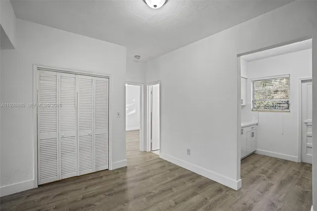 an empty room with wooden floor & closet area