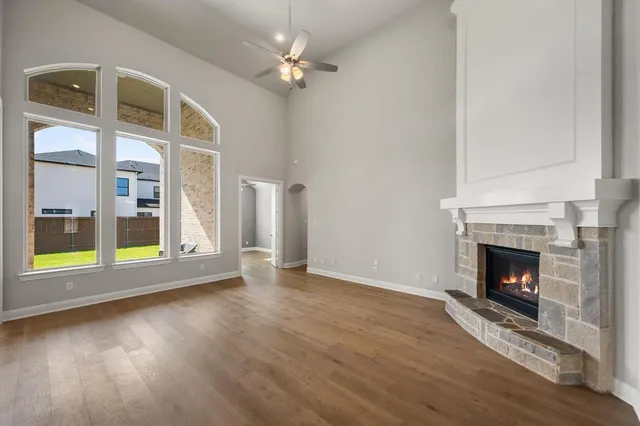 a view of an empty room with wooden floor fireplace and a window