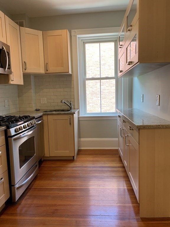 38 Kilsyth Road, Unit 33 Brookline, MA 02445 - Photo 12 of 23 a kitchen with granite countertop a stove a sink and a microwave