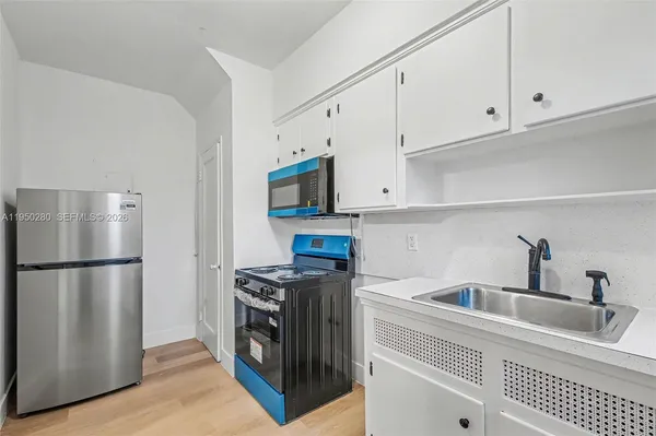 a kitchen with stainless steel appliances granite countertop a refrigerator a stove a sink and white cabinets