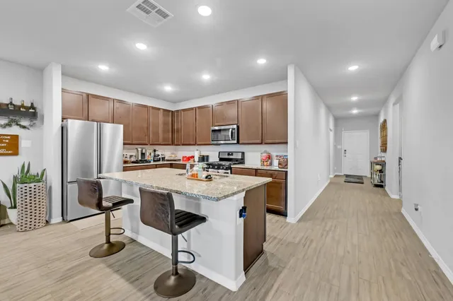 a kitchen with stainless steel appliances kitchen island hardwood floor sink and stove