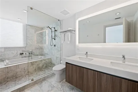 a bathroom with a double vanity sink toilet mirror and bathtub