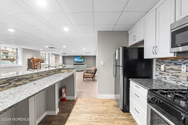 a dining hall with stainless steel appliances a large window and a kitchen view