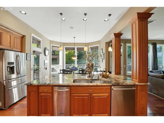 a kitchen with stainless steel appliances kitchen island granite countertop a table chairs and a refrigerator