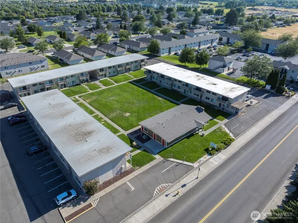 an aerial view of a tennis ground and a cars park side of the road
