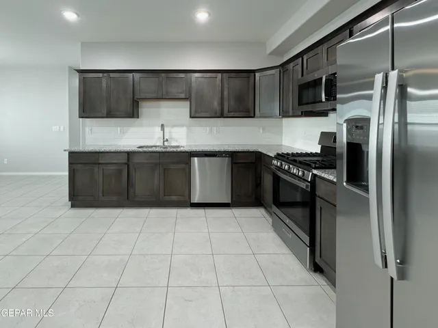 a kitchen with granite countertop a refrigerator and a stove top oven