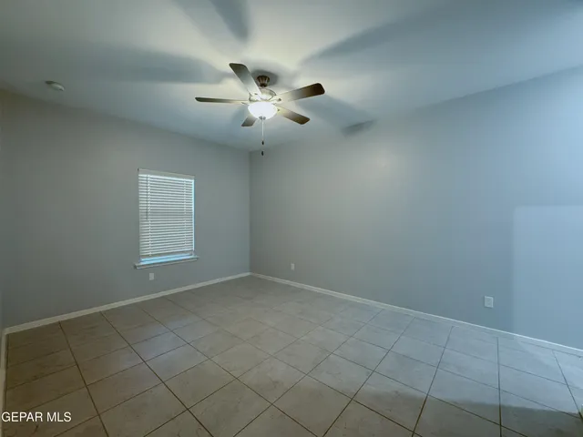 an empty room with windows and chandelier fan