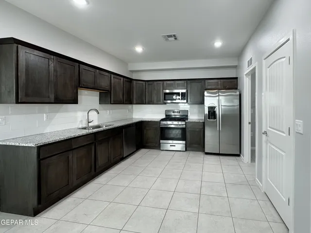 a kitchen with granite countertop a refrigerator and a sink