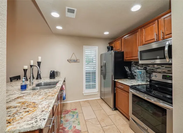 a kitchen with stainless steel appliances kitchen island granite countertop a stove refrigerator and microwave