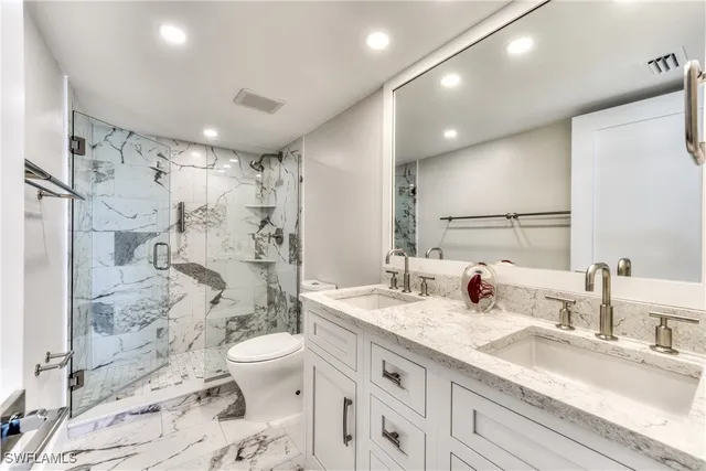 a bathroom with a granite countertop sink a toilet a shower and a mirror