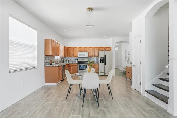 a dining room with stainless steel appliances kitchen island granite countertop a dining table chairs and granite counter tops