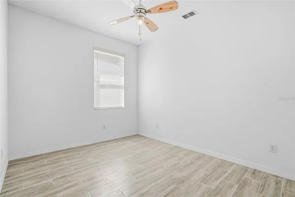 an empty room with a window and a ceiling fan