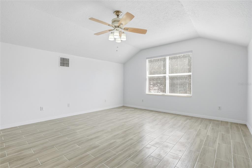 12351 Ridgedale Drive Hudson, FL 34669 - Photo 38 of 48 an empty room with wooden floor chandelier fan and windows