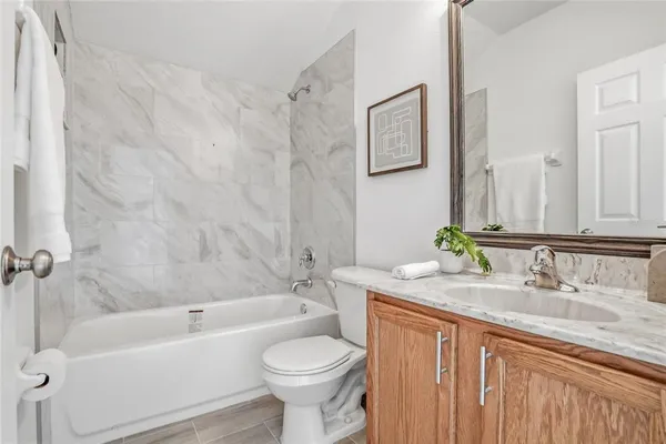 a bathroom with a granite countertop sink toilet mirror and bathtub