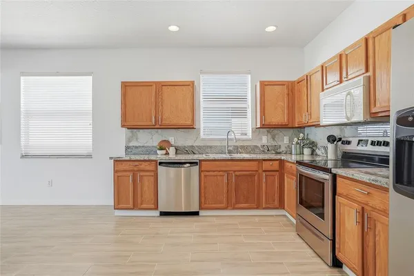 a kitchen with stainless steel appliances granite countertop a stove a sink and a microwave