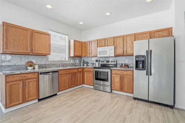 a kitchen with granite countertop a refrigerator stove top oven and sink