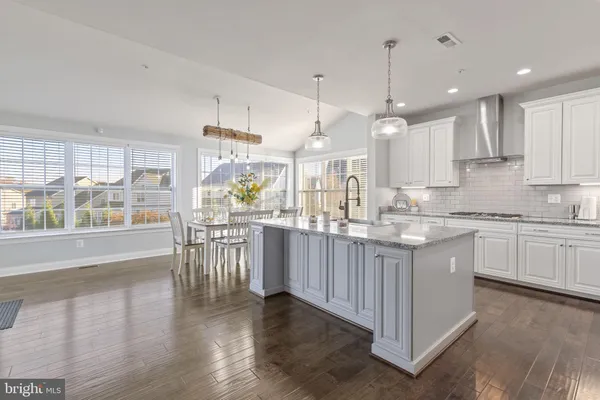 a kitchen with stainless steel appliances kitchen island granite countertop a white cabinets and wooden floors