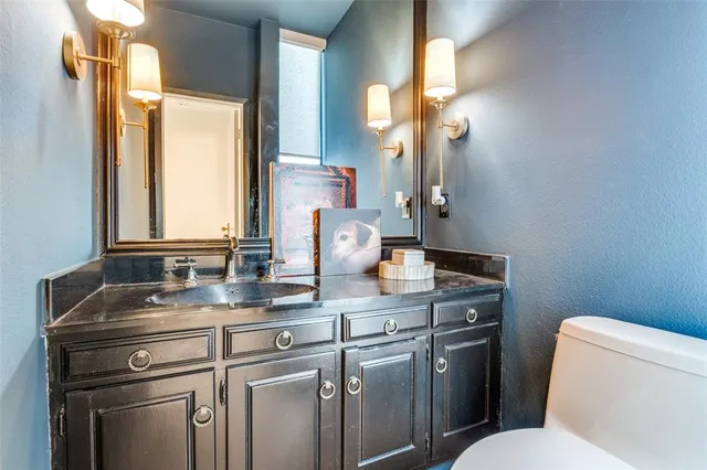 a bathroom with a granite countertop toilet sink and mirror