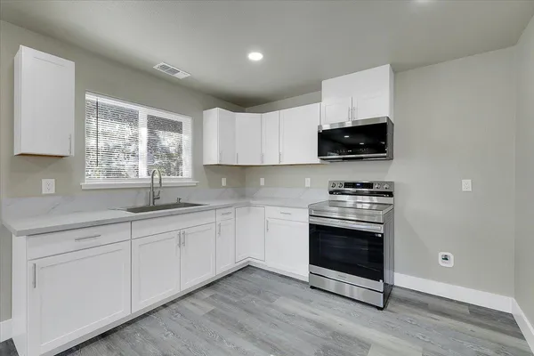a kitchen with stainless steel appliances granite countertop a stove a sink and a microwave