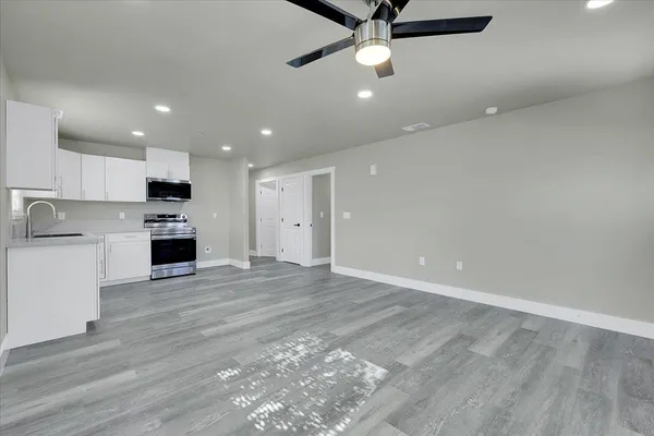an open kitchen with kitchen island a island wooden floor stainless steel appliances and cabinets