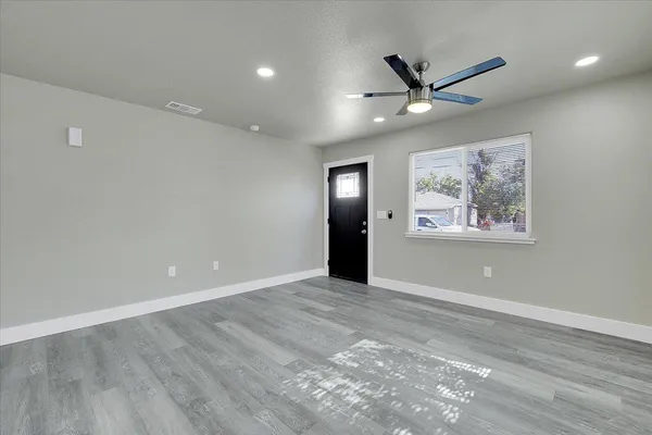 a view of an empty room with a ceiling fan and window