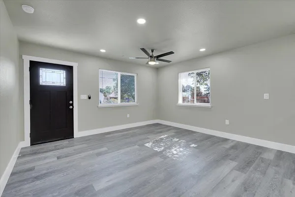 a view of an empty room with wooden floor and a ceiling fan