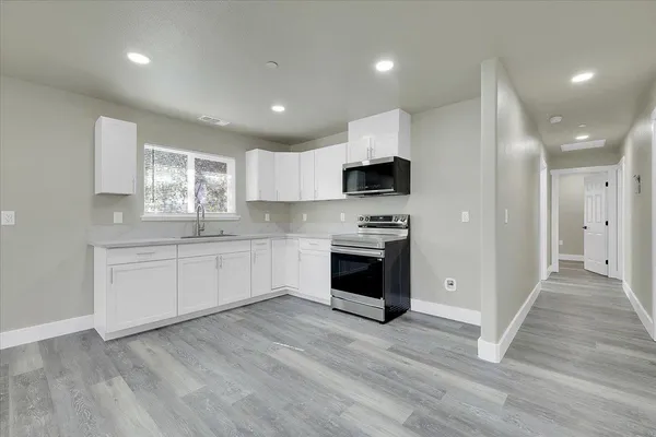 a kitchen with granite countertop a sink cabinets and stainless steel appliances