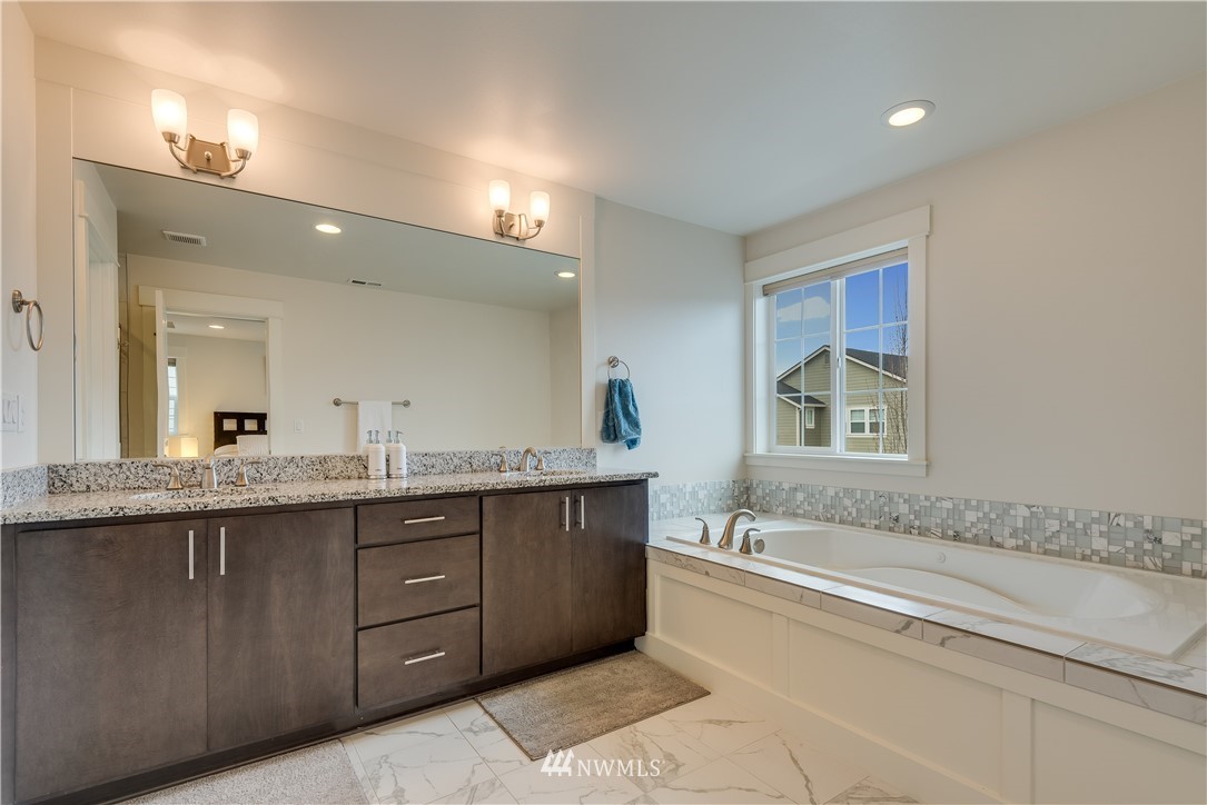 4408 186th Street Southeast Bothell, WA 98012 - Photo 16 of 23 a spacious bathroom with a granite countertop double vanity sink and mirror with bathtub